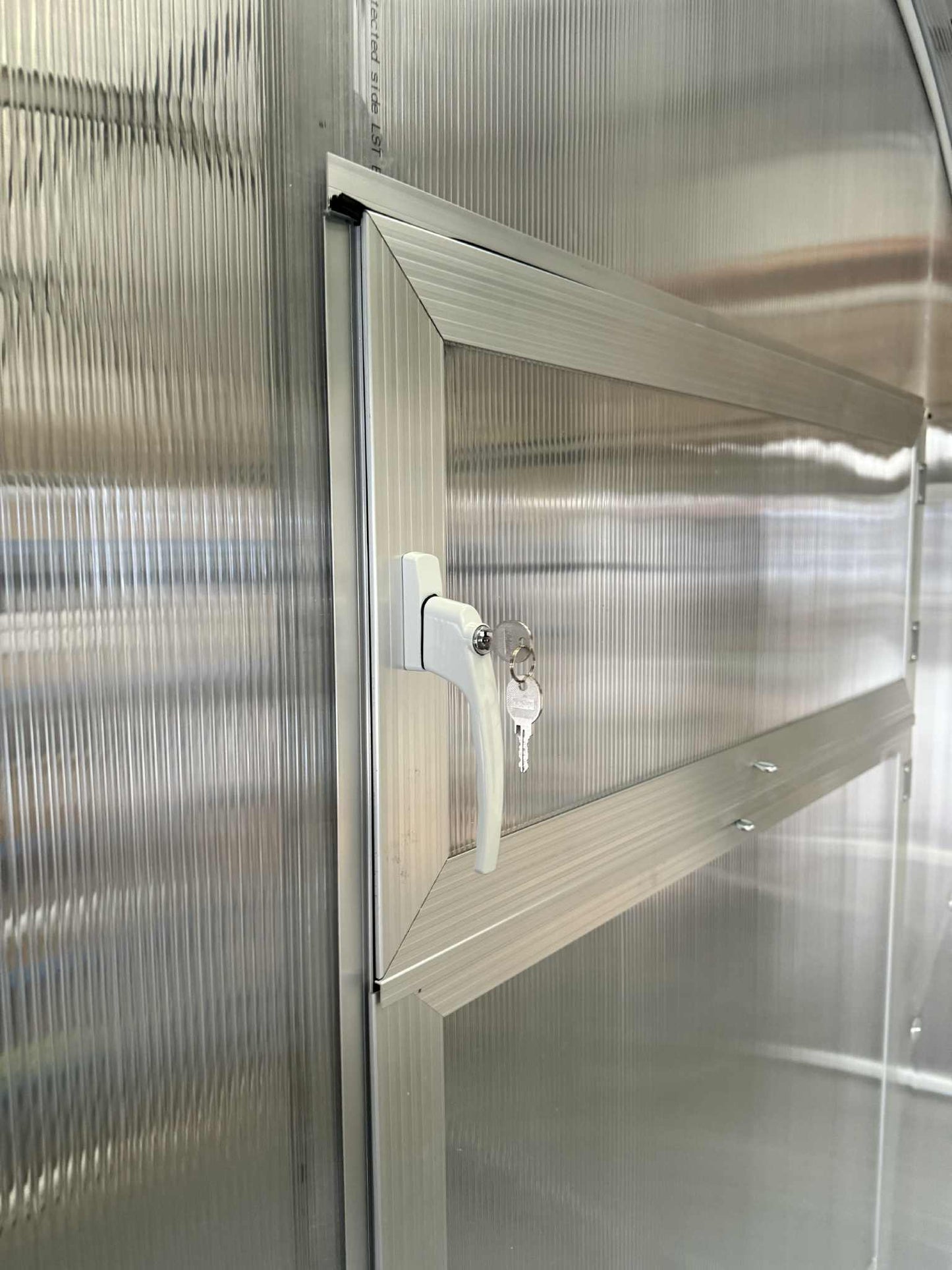 Metallic door with a handle and key lock on a Sigma 200 (Gen III) greenhouse door.