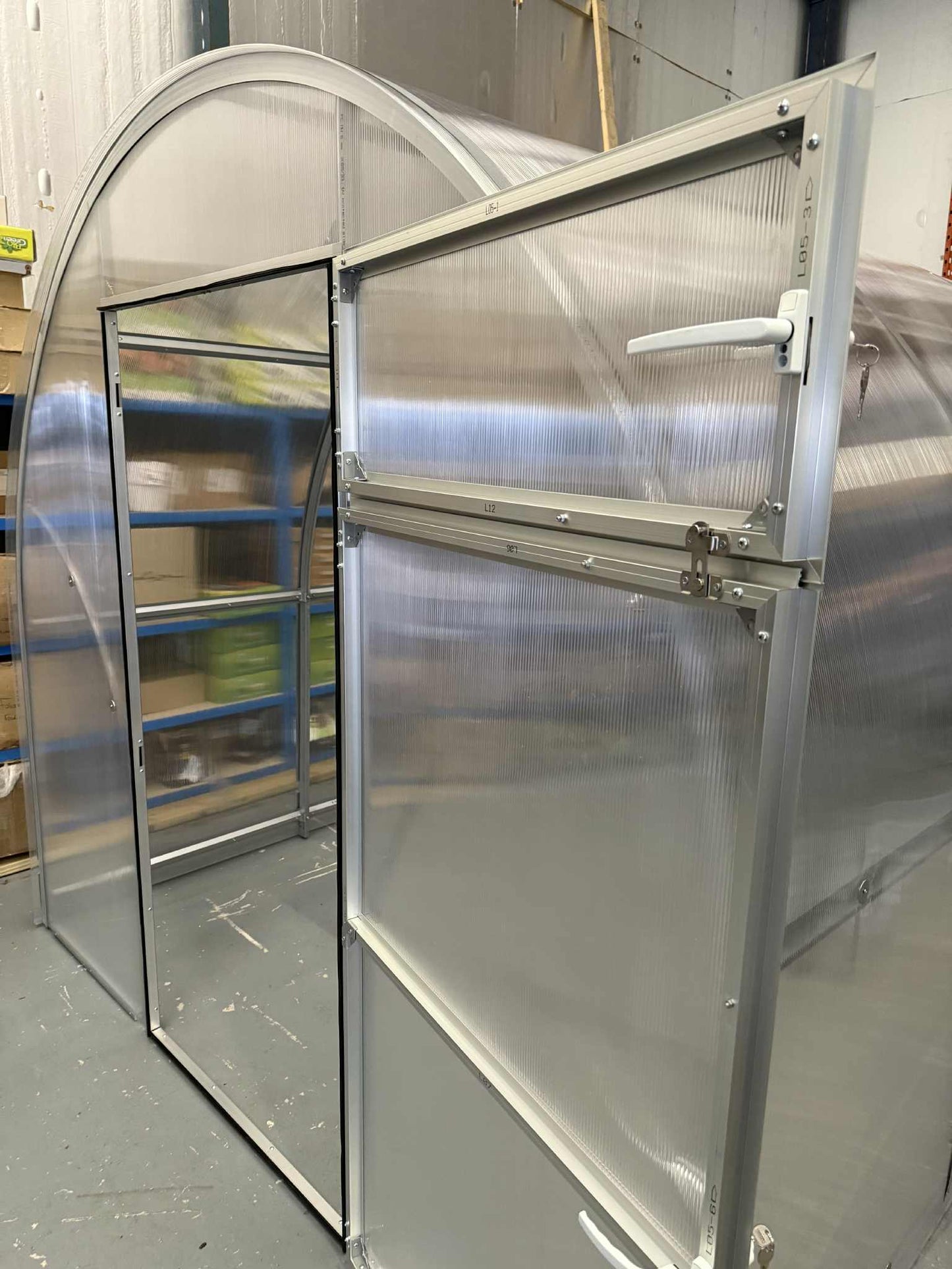Metallic Sigma 250 (Gen III) greenhouse with a sliding door in an indoor setting