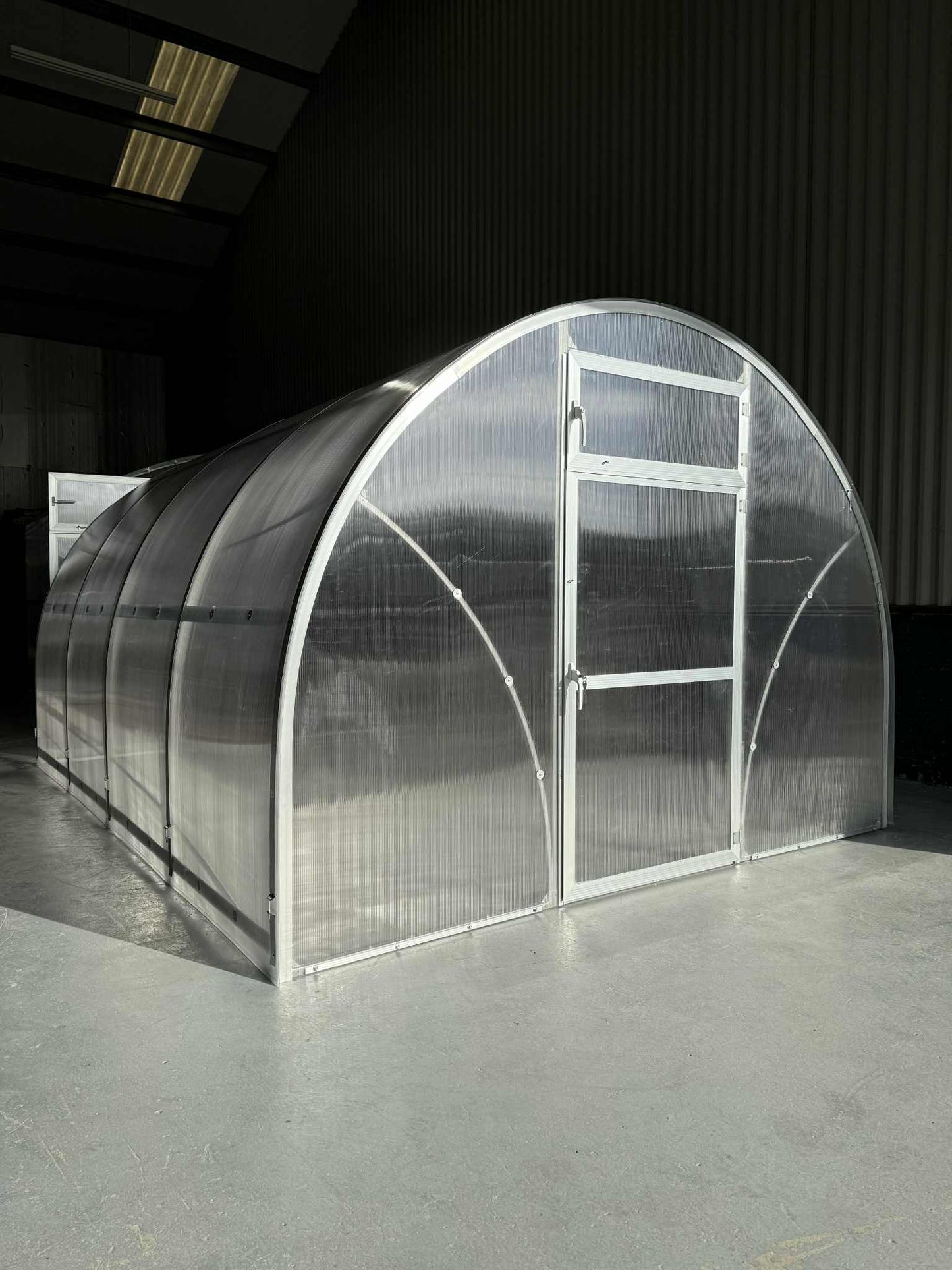 Large transparent Sigma 300 (Gen III) greenhouse with metal frame in a warehouse setting